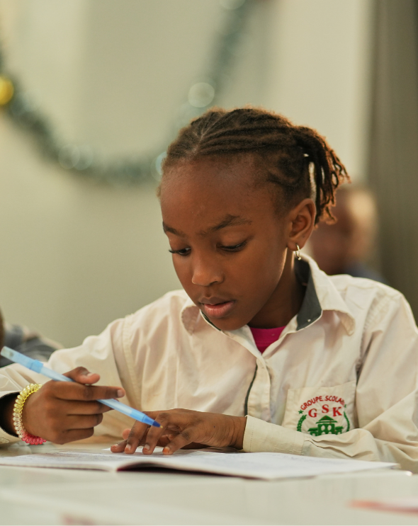 Élève du Groupe Scolaire Kambal en classe, concentration sur le travail scolaire